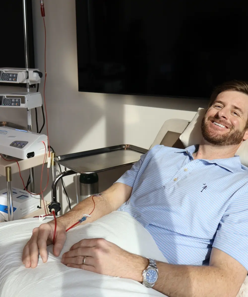 Smiling patient receiving IV therapy in a treatment chair